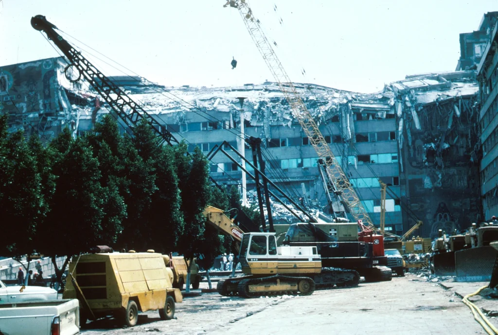Collapsed upper stories and construction equipment at work at the Ministry of Telecommunications and Transportation building.
