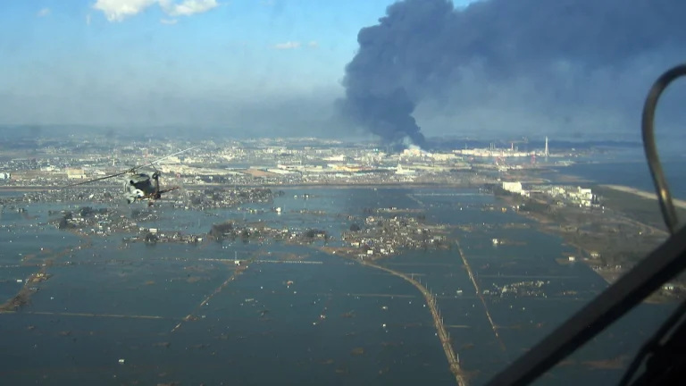 A helicopter flies over the port of Sendai to deliver food to survivors of the earthquake and tsunami