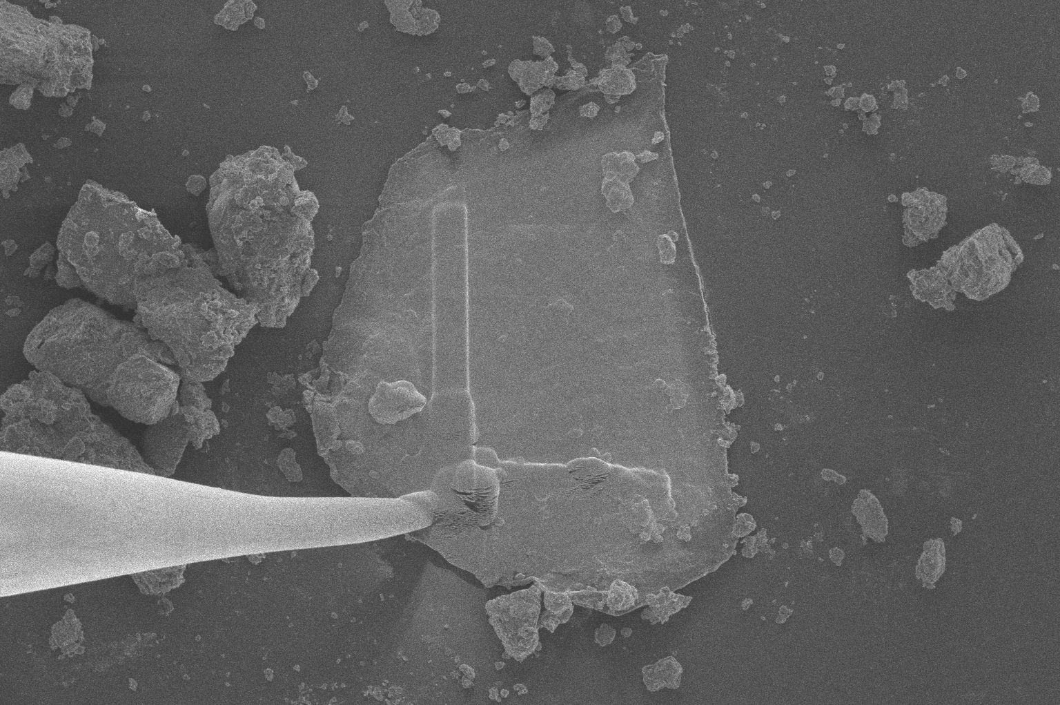A microscopic particle of asteroid Bennu, brought to Earth by NASA’s OSIRIS-REx mission, is manipulated under a transmission electron microscope