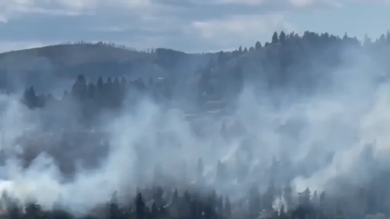 A plume of smoke from the Kalamoir Park wildfire is visible above West Kelowna, British Columbia, on June 16, 2026