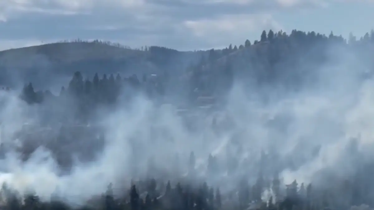A plume of smoke from the Kalamoir Park wildfire is visible above West Kelowna, British Columbia, on June 16, 2026
