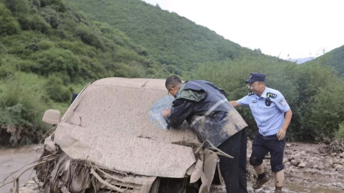 Rescue operative searching vehicles for trapped people after deadly flooding in Dingxi City in Gansu Province, China on July 26, 2026